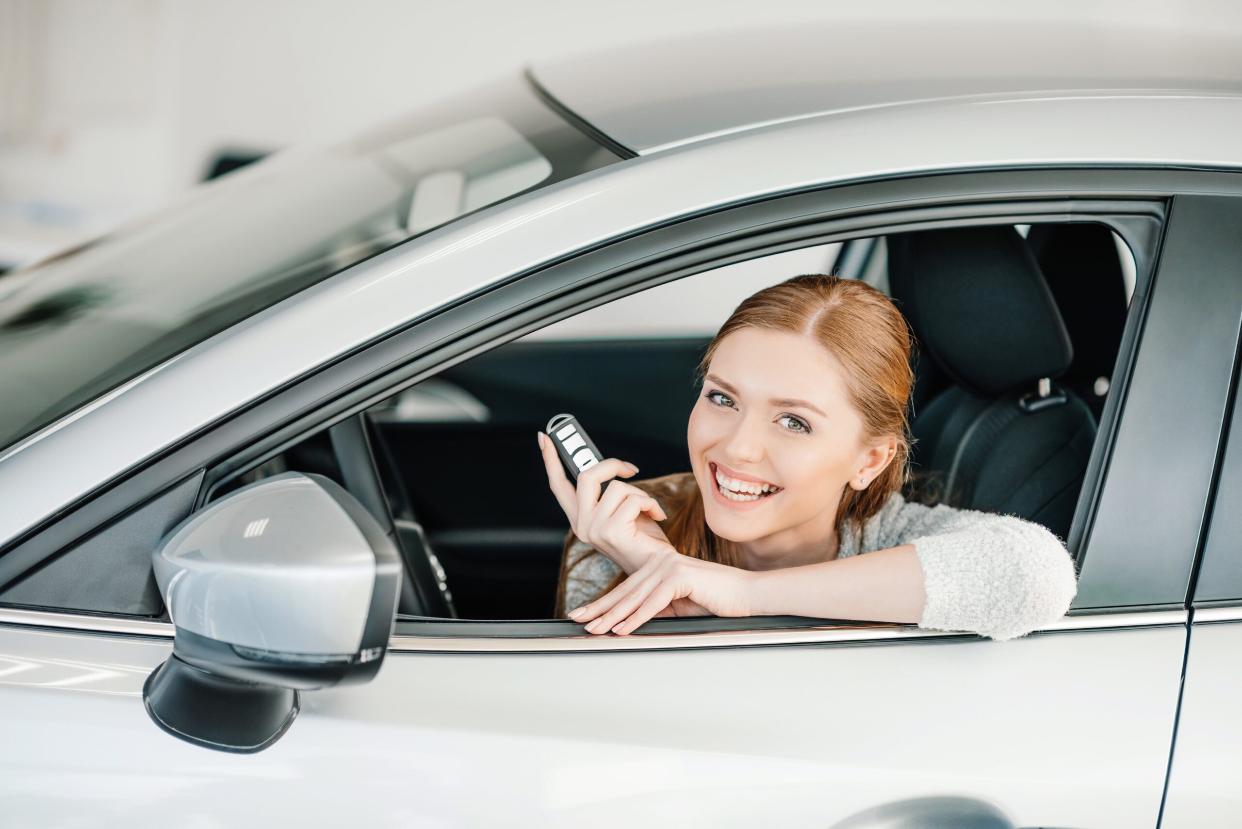 happy-young-woman-with-key-sitting-in-ne